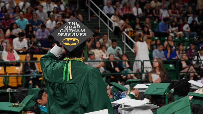 A graduate in green shares the words on his graduation cap.