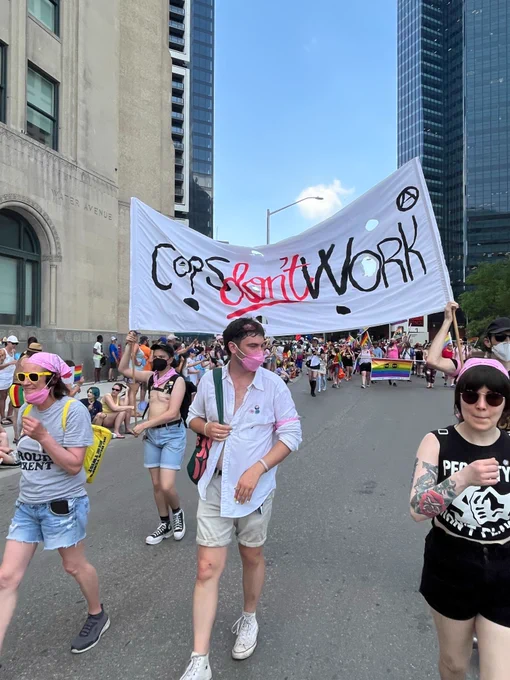 Several people walk in front of the "cops don't work" banner