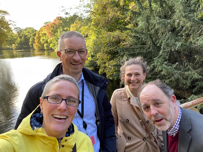 A group photo of Ronald Snijder, Laura Wilkinson, Lucy Montgomery and Cameron Neylon standing on a bridge in The Hague, the Netherlands. The photo is taken in 'selfie' style - with Laura holding the camera. Everyone is smiling, except for Cameron, who is leaning towards the camera trying to get in shot.
