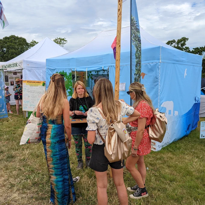 Ali Birkett talking with a group of Fascinated festival goers outside a brightly coloured marquee