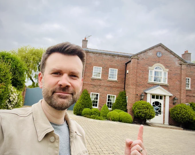 Director of Epix Media, Will King, stood in front of a large brick built country home, with neat green shrubs and trees and a block paved driveway