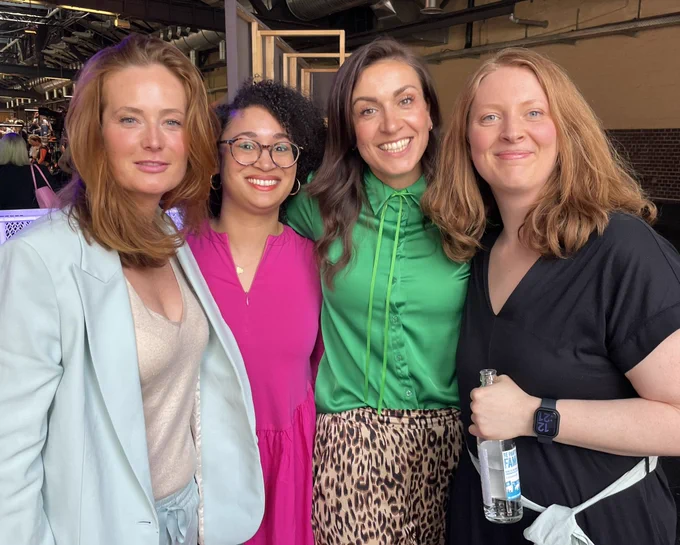 Auf dem Bild stehen Nina Strassner (blauer Anzug), Sara Weber (pinkes Kleid), Lena Rogl (grüne Bluse) und Sue Reindke nach ihrem republica Panel im Backstage Bereich und lächeln in die Kamera.