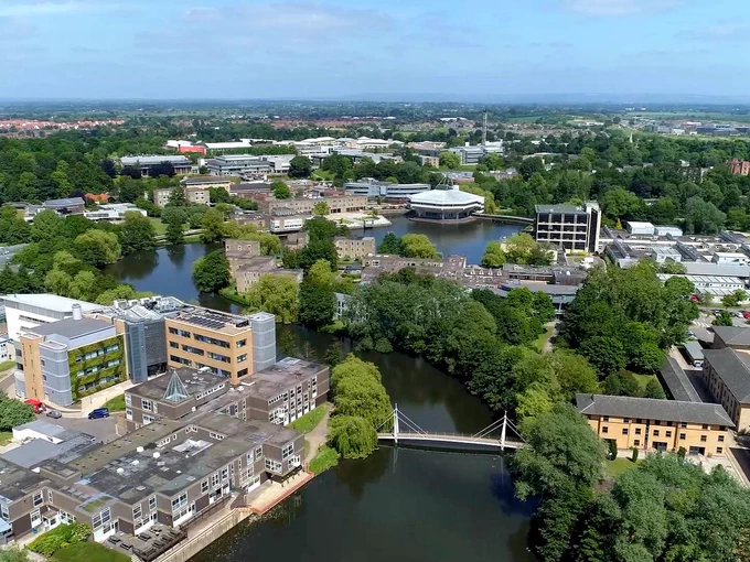 An aerial view of Campus West, with buildings and huge amounts of greenery scattered around the lake. 