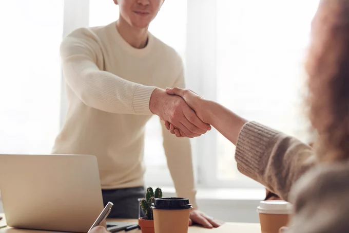 Two business people in casual dress shaking hands. 