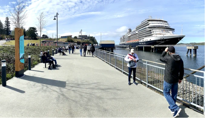 Cruise ship along the river where pedestrians walk.