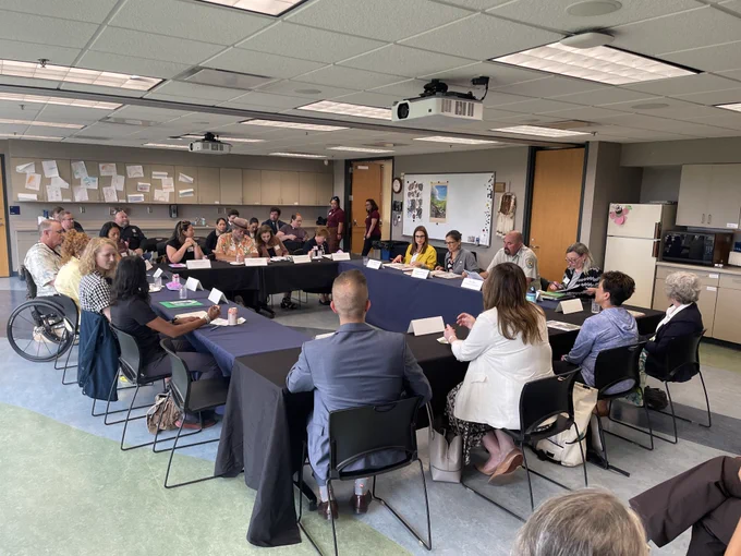 Secretary Haaland and group of people sitting around a table discussing equity in outdoor recreation.