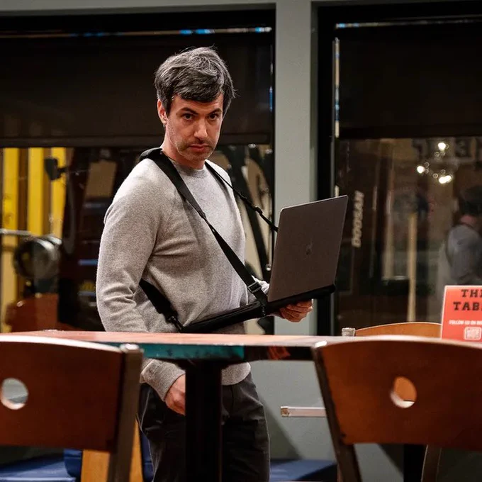 nathan fielder with a laptop in a harness