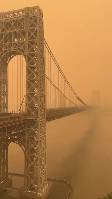 Image shows a NYC bridge coveted completely in smoke in sepia tone