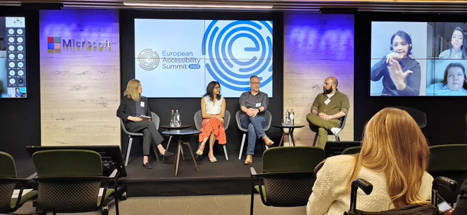 Speakers sat in front of the background of the European Accessibility Summit