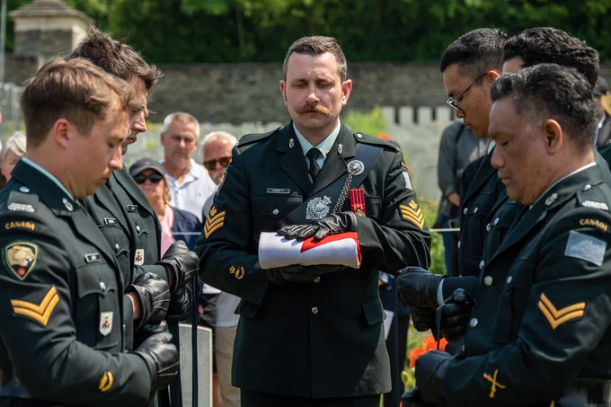A Canadian Armed Forces soldier holds a folded Canadian flag.
