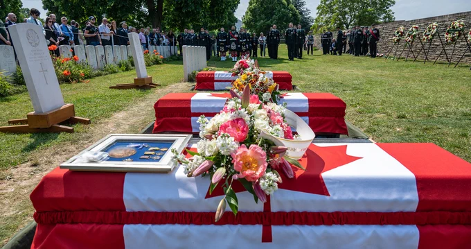 Red and white Canadian flags drape the caskets of three Canadian soldiers of the First World War.