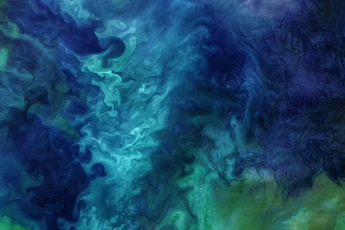 Landsat 8 image of swirls of teal, turquoise, and green phytoplankton blooms in the Chukchi Sea off the Alaskan coast in 2018. 