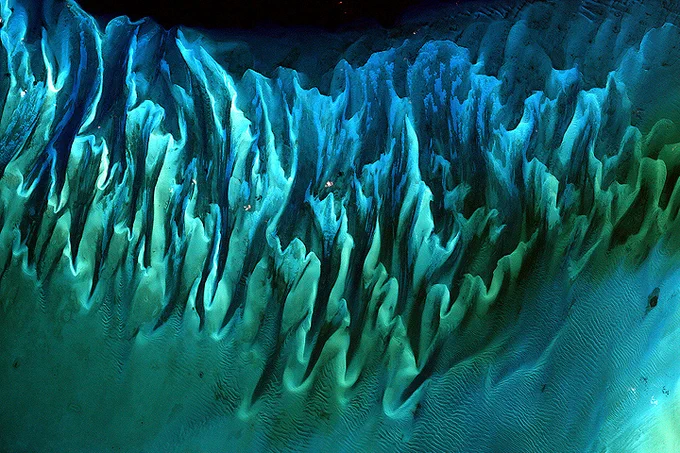 Landsat 7 image of an intricate network of sand dunes on the ocean floor near the Great Bahama Bank. The dunes form blue, teal and green structures that look like waves and squiggles on the seafloor.
