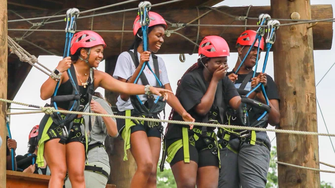 Four students stand together on a ropes course.