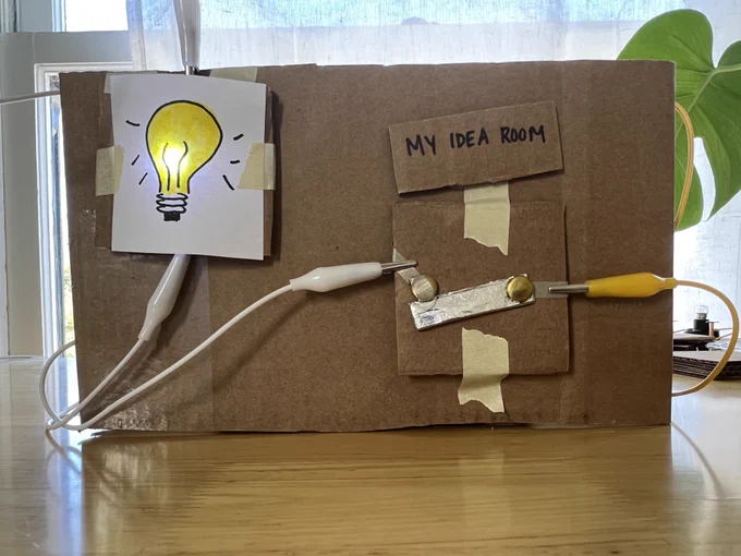 A project called My Idea Room made out of cardboard with a light up bulb drawing 