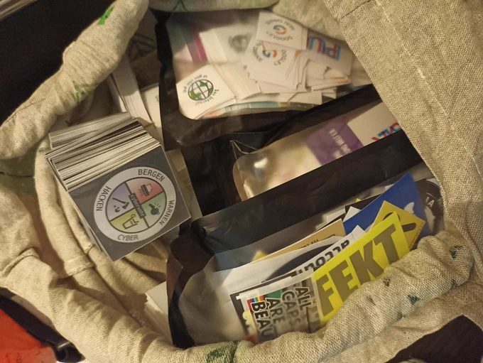 a jute bag with stacks and plastic bags full with different stickers