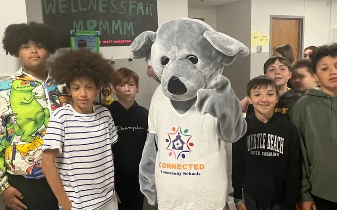 Group of students surrounding costumed bear mascot