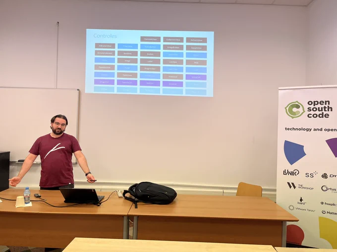 Ponente tras una mesa con slide con muchos controles de la plataforma MAUI y banderola del OpenSouthCode