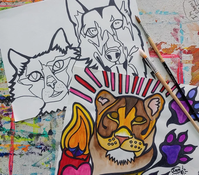 One black and white sketch of a cat and a service German Shepherd Dog and one colorful sketch of a lioness positioned partly off to the side with two paint brushes. The sketches are laid upon a board with many colors of dripped paint. Photo and Design Credit: Susan Bagrationoff, Owner and Artist, Artsy Fartsy Art Lessons, 2023. Featured on the promotional sketch are three beloved animals interred at the historic Seattle-Tacoma Pet Cemetery: Cat "Sasha", K-9 Officer Captain "Cap" Hofstra, and our Vegetarian Lioness "Little Tyke"! 