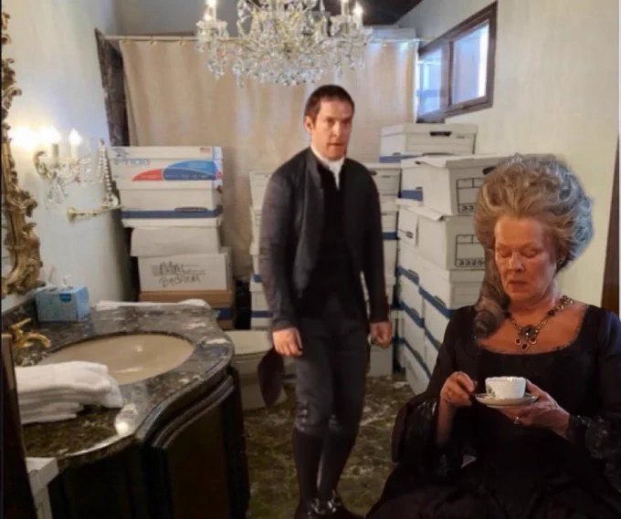 Mr. Collins awkwardly bows to Lady Catherine de Bourgh in a gaudy marble and gold bathroom at Mar-a-Lago that outdoes even Rosings Park in its garishness. He stands under a crystal chandelier and in front of a stack of white banker’s boxes. From Pride and Prejudice (2005).