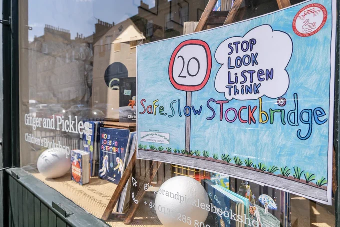 A children’s drawing mounted in the window of a book shop in Edinburgh reads “Safe Slow Stockbridge: Stop, Look, Listen, Think”.