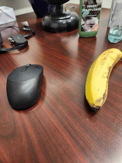 Office desk with a computer mouse and a banana next to each other. 