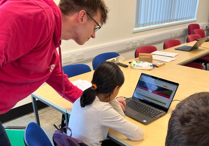 Code for Life team member helping a female student get started with Rapid Router on a laptop.