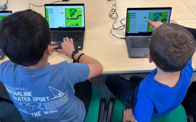 Two boys trying out some coding with Rapid Router on some laptops.