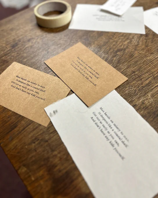 Three brown postcards on a table, with the following four lines from ‘This be the Verse’ by Philip Larkin printed on them:

Man hands on misery to man. 
It deepens like a coastal shelf.
Get out as early as you can,
And don’t have any kids yourself.