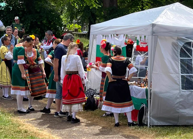 Picture of lots of people standing around the Bulgarian stand, some wearing their national dress.