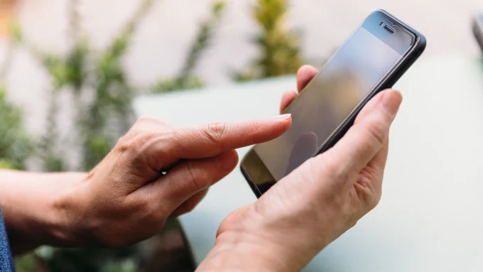 Person tipp mit dem Zeigefinger auf ein Smartphone