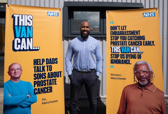 Sotanye Tolofari a black man with a shaven head, stands between to pull up banners containing the ThisVanCan logo. One features Fin, a white man with glasses and a shaven head, and says 'ThisVanCan help dads talk to sons about prostate cancer' and a second banner features Winston, a black man with grey hair and glasses, and says 'Don't let embarrassment stop you catching prostate cancer early. ThisVanCan stop us dying of ignorance.'