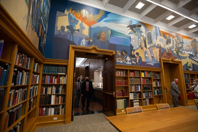 Reading Room in the Lilly Library, featuring murals on the top half of the walls over tall bookshelves filled with books.