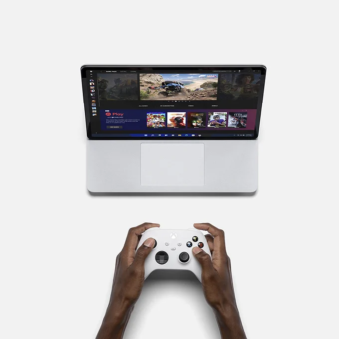 une personne qui joue à son jeu Xbox avec sa manette sur son ordinateur surface laptop studio