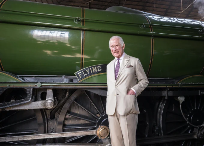 The King stands by the steam train engine, the flying scotsman