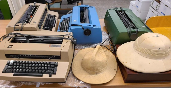 A view of the Archivist's processing table: on it we see three typewriters and two hats.