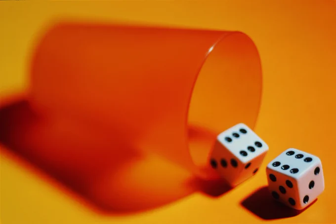 Dice rolling out of an orange cup.