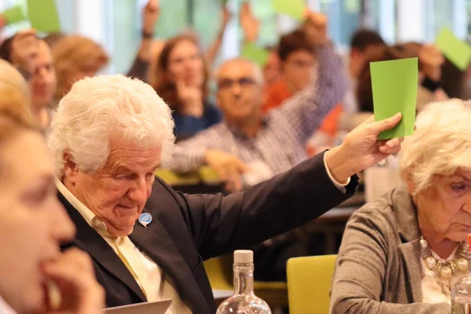 Participant to the EDF Annual General Assembly holds up a green card - participants in the background are doing the same