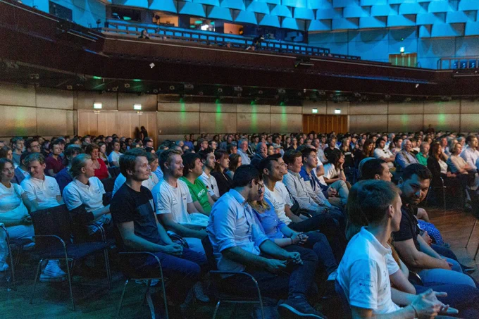 Sitzende Personen in einem großen Saal.