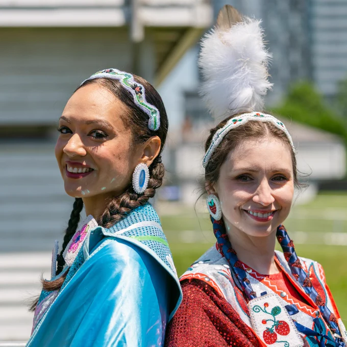 Two dancers smiling outdoors at Indigenous Arts Festival 2022.