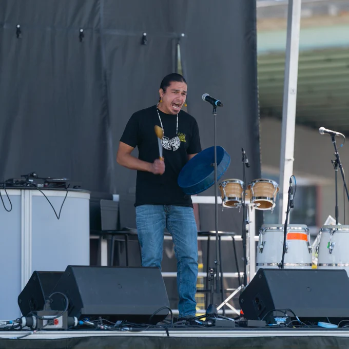 Performer on stage with a drum at Indigenous Arts Festival 2022. 