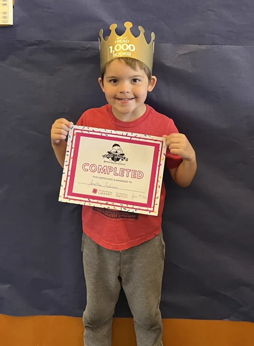 Presenting Jonathan, King of the Books! (Kindergartner Jonathan holds his "completed" certificate while wearing his crown)

He earned his title as King after winning "The Battle of the 1,000 Books". How did he defeat the books? 
He read them... 1,000 books! WOW 🤩

Congratulations, King Jonathan! 1,000 books before kindergarten. We're happy for you, so proud of you 📚