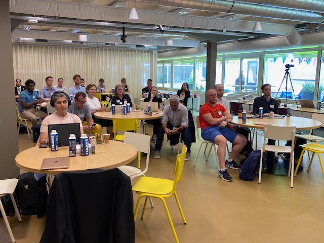On-site attendees at Atlassian office in Amsterdam. Groups of people at round tables at the IAAP EU accessibility event.