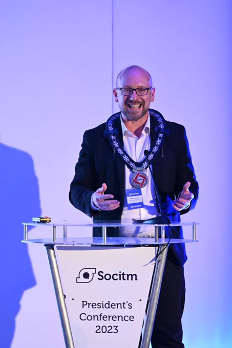 Man standing at a podium smiling.