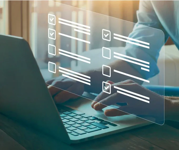 Close up of man's hands and arms working on a laptop computer. Illustration of screen show rows of text and checkmark boxes. Some boxes have check marks and others do not. 