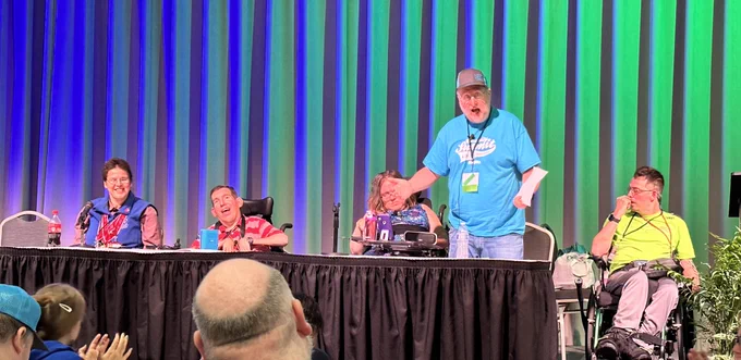Five people on stage getting ready to present.