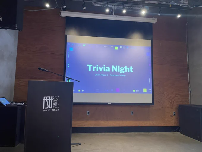 Trivia night slide projected on screen on Outback Shack stage at Fanshawe College.