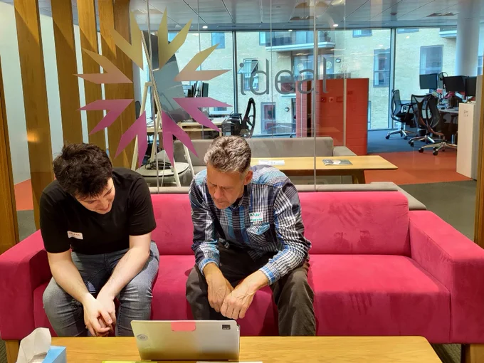 two codebar organisers on a pink sofa considering a problem on a laptop