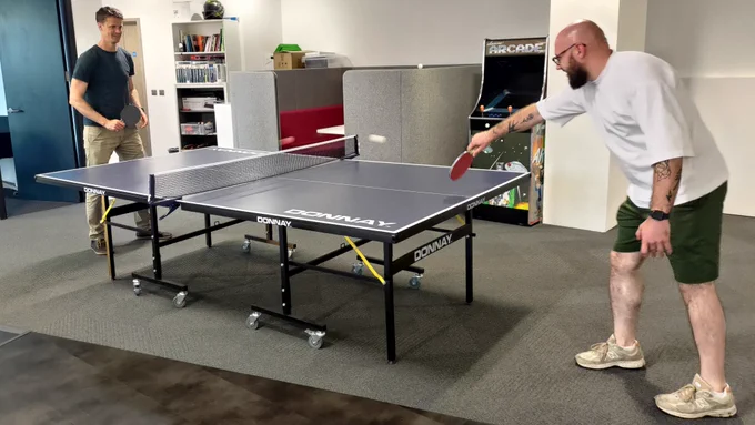 two male employees of ideal are playing table tennis in the office