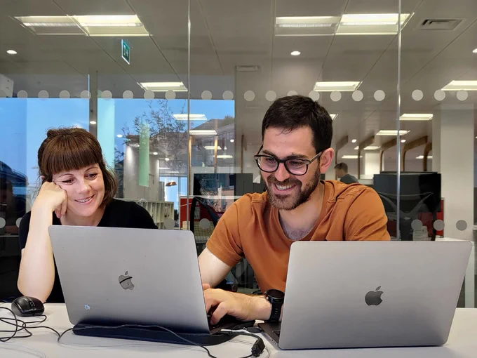 smiling white woman and man are looking at a laptop screen together